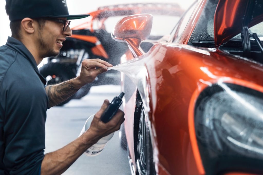 Person polishing a car body panel in a garage