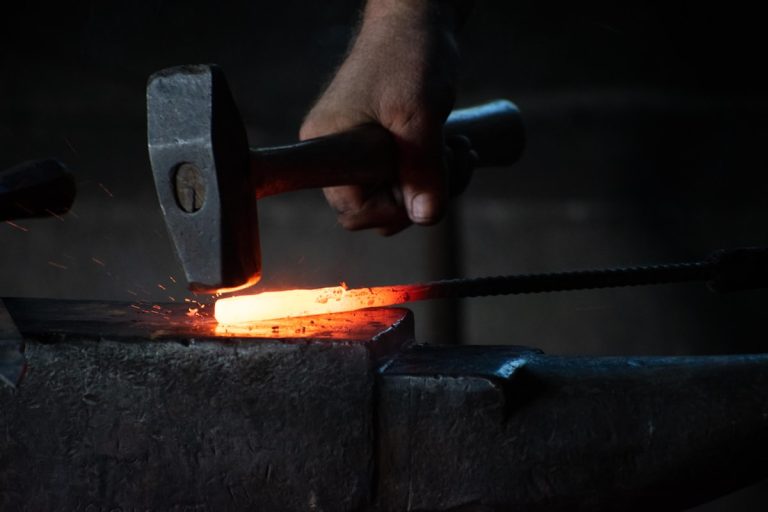 Metalworker hammering hot steel at a forge