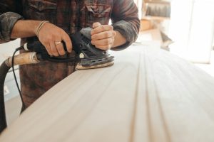 Person using a sander on a smooth wooden surface